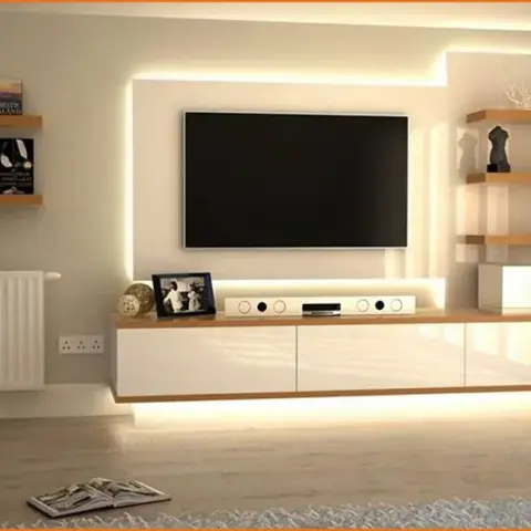 Living room TV wall with a floating white gloss console, warm LED backlighting, and open wood corner shelving.