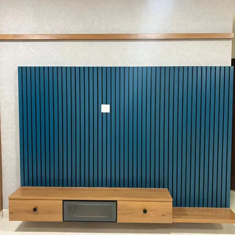 Living room TV wall with a teal-blue fluted panel accent above a floating wood console with two drawers and an open cubby, beside the entrance door.