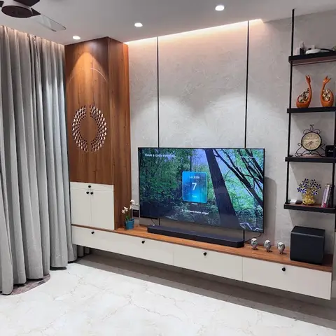 Living room TV wall with a textured grey stone-effect panel, a wood accent column with a circular metal wall sculpture, a floating cream-and-wood TV console