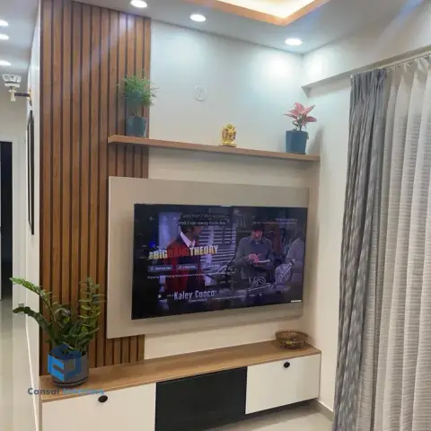 Living room TV wall with a fluted wood panel accent strip, a floating wood shelf styled with plants and a small idol, and a two-tone TV unit below.