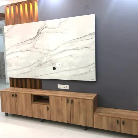 Living room TV wall with a bookmatched white marble slab panel on a charcoal-grey wall, a wood-slat ceiling feature