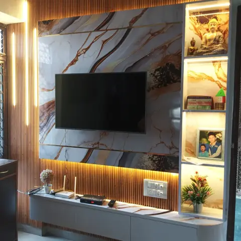 Living room TV wall with a gold-veined marble-effect backdrop framed by fluted wood panelling, and backlit display niches styled with a Buddha statue