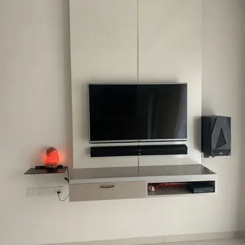 Living room TV wall with a floating console housing a soundbar and subwoofer, a thin gold inlay strip on the panel