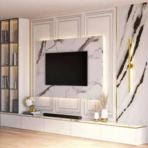 Living room TV wall with a book-matched marble panel framed in gold-trimmed classical moulding, flanked by dramatic black-veined marble and a brass wall sconce.