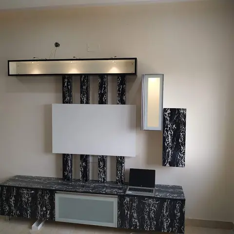 Living room TV wall with black-and-white marble-effect panelling framed by fluted pillars