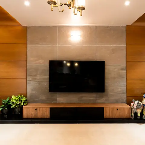 Living room TV wall with book-matched wood panelling flanking a stone-clad feature wall, a walnut-and-black lacquer TV console
