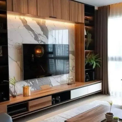 Living room TV wall with book-matched marble cladding, floating wood console with cove lighting, and open shelving styled with plants.