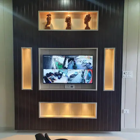 Living room TV wall with dark fluted wood panelling, backlit display niches holding carved wooden bust sculptures
