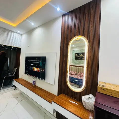 Living room TV wall with fluted wood panelling and a backlit oval mirror set into a matching wood-panelled console