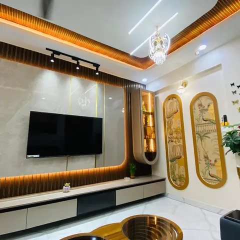 Living room TV wall with gold-trimmed fluted wood panelling and a marble backdrop, under a cove-lit wood-slat ceiling