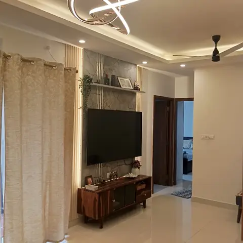 Living room TV wall with grey-veined marble cladding flanked by brass fluted strips, a sculptural ring chandelier overhead