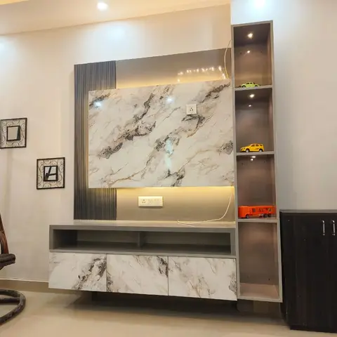 Living room TV wall with marble-effect panelling and an open display shelf styled with toy cars, beside a rattan hanging swing chair.