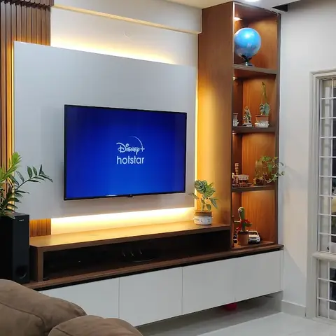 Living room TV wall with vertical fluted wood panelling, a backlit TV panel and an open display shelf styled with curios and plants.