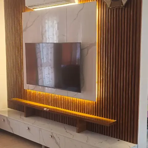 Living room TV wall with vertical fluted wood panelling, a backlit marble-look panel and a floating marble-finish console