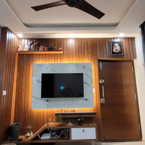 Living room TV wall with vertical wood fluted panelling framing a backlit marble panel behind the television, an angled wood console below