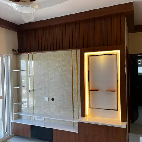 Living room TV wall with wood-slat panelling, a cream marble panel edged in gold inlay strips, and an amber backlit display niche beside it