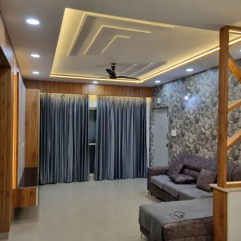 Living room under a stepped cove-lit POP ceiling, with a teak-panelled wall carrying an LED reveal down to a floating ledge