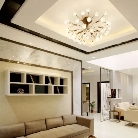 Living room under a stepped cove-lit false ceiling with dark glossy border bands and a brass sputnik chandelier