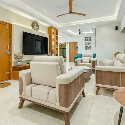 Living room viewed from the teak main door with a horseshoe nailed above it: cream-and-walnut sofa set on cream marble