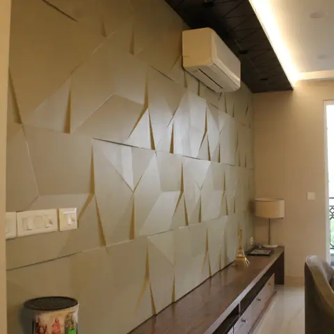 Living room wall clad in beige faceted 3D panels running the full length behind a low walnut console
