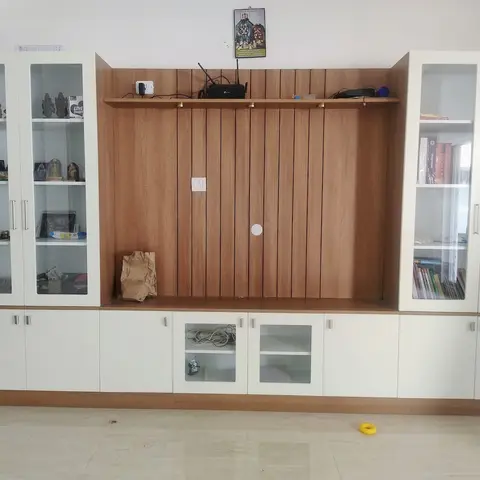 Living room wall unit with a fluted wood-panel TV niche flanked by glass-front display cabinets holding curios and books.
