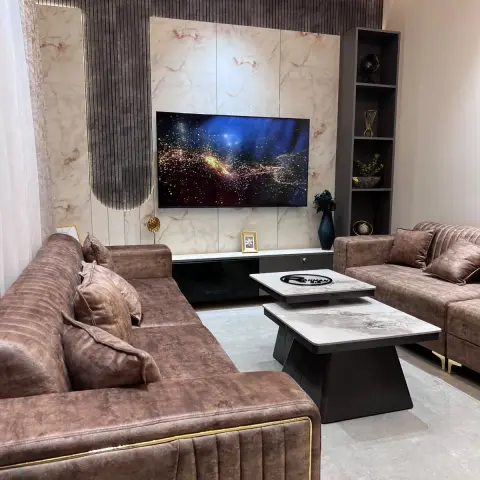 Living room where a brown fluted-wood wall wraps an arch motif around a pink-veined marble TV panel