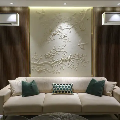 Living room where a hand-carved white plaster relief of blossom branches and two birds fills a backlit