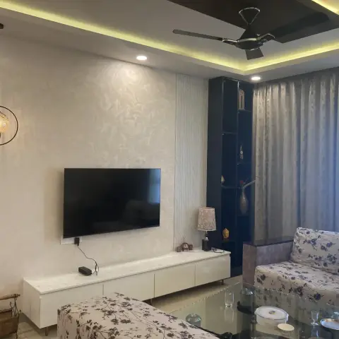 Living room where a wall-hung TV sits on cream textured floral wallpaper above a glossy white low console