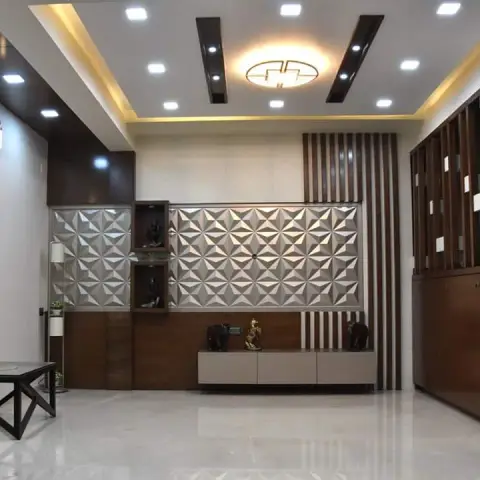 Living room with a 3D geometric feature wall flanked by display niches holding brass idols, a wood-slat partition screen, a wood console below
