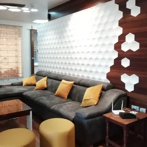Living room with a 3D white honeycomb-panelled feature wall transitioning into dark wood cladding