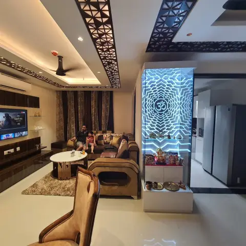 Living room with a backlit acrylic Om-motif pooja cabinet used as a glass partition to the kitchen