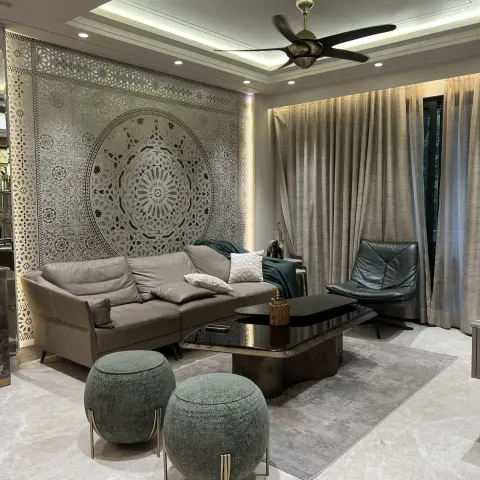 Living room with a backlit carved mandala jaali panel filling the wall behind a taupe leather sofa