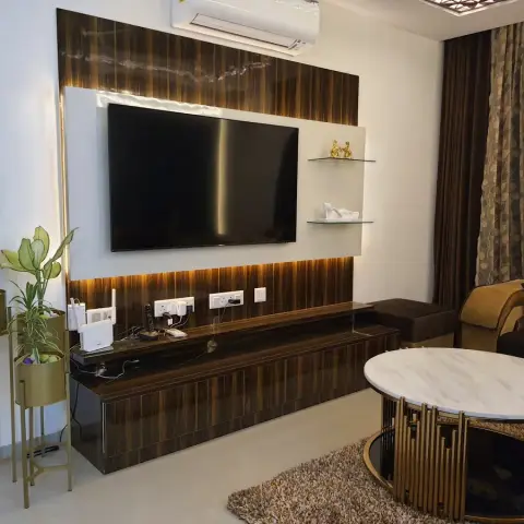 Living room with a backlit dark-wood-veneer TV unit, glass display shelves styled with decor
