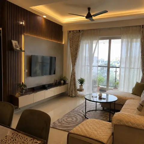 Living room with a backlit wood-fluted TV wall, a floating console below, a beige quilted L-shaped sectional sofa around a round marble-top coffee table on a