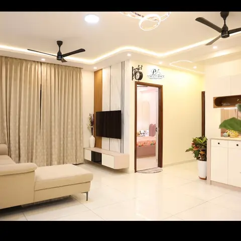 Living room with a beige chaise sofa facing a floating TV console on a marble-and-wood-strip wall, cove ceiling lighting with a ring pendant