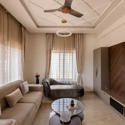 Living room with a beige channel-tufted sofa facing a grey velvet chaise, twin kidney-shaped coffee tables on marble-look tile
