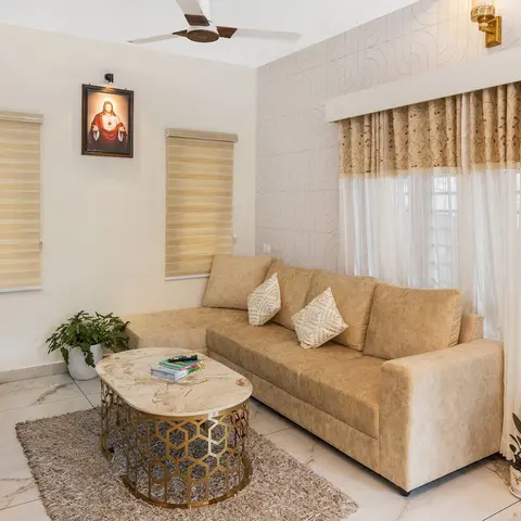 Living room with a beige L-shaped sofa and gold-hexagon marble coffee table, set against a textured geometric-patterned accent wall with a brass sconce