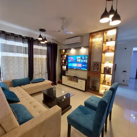 Living room with a beige L-shaped sectional sofa with teal cushions, a glass-top coffee table on a dark wood base