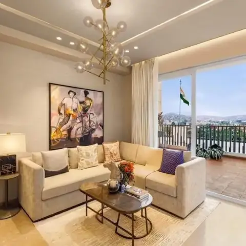 Living room with a beige L-shaped sofa and an oval wood-glass coffee table beneath a gold bubble chandelier, a large figurative painting on the wall