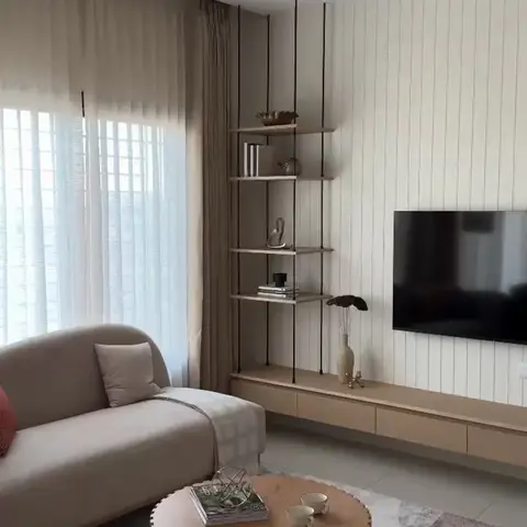 Living room with a beige sofa and rust-colored accent sofa around a fluted round coffee table, a hanging ladder-style display shelf