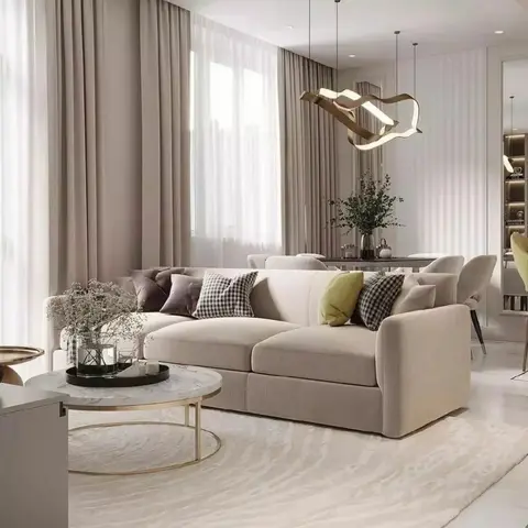 Living room with a beige textured sectional sofa styled with checkered and velvet cushions, a round marble-and-brass coffee table