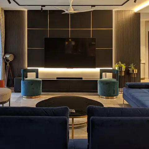 Living room with a black and brass grid-panel TV wall, a navy velvet sectional sofa, emerald velvet stools, a rust-orange armchair