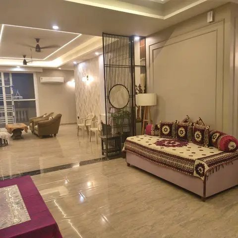 Living room with a black metal jaali screen divider set with a round mirror beside a diwan-style sofa with traditional print upholstery