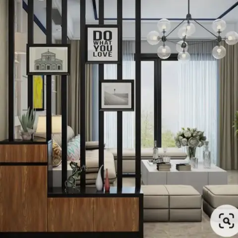 Living room with a black metal-slat partition dividing a wood-and-black console styled with framed art from a beige sofa seating area