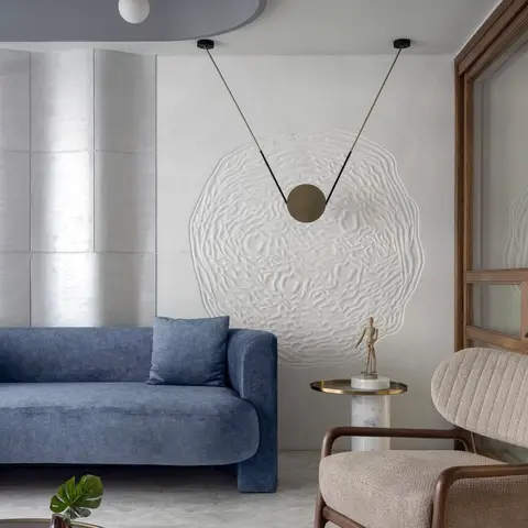 Living room with a blue velvet sofa, a sculptural cream 3D-textured wall art piece hung with a pendant disc lamp