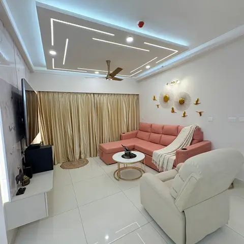 Living room with a blush pink L-shaped sofa and cream recliner facing a marble-effect TV wall, under a linear-lit geometric false ceiling