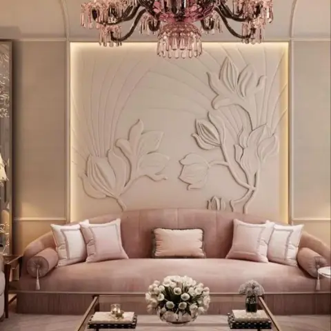 Living room with a blush pink curved sofa beneath an oversized floral relief wall panel and a pink crystal chandelier.