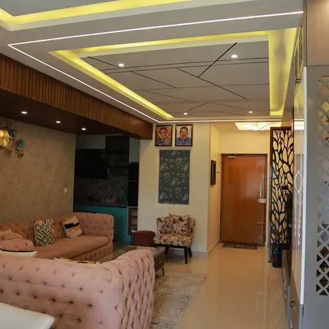 Living room with a blush-pink tufted chesterfield sofa under a geometric cove-lit false ceiling