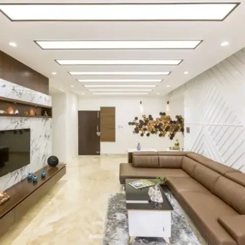 Living room with a book-matched white marble TV wall framed in walnut, a tan leather L-sofa on a grey shag rug