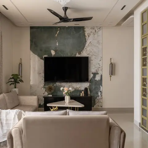 Living room with a book-matched green marble TV feature wall, beige velvet sofas, a black fluted TV console